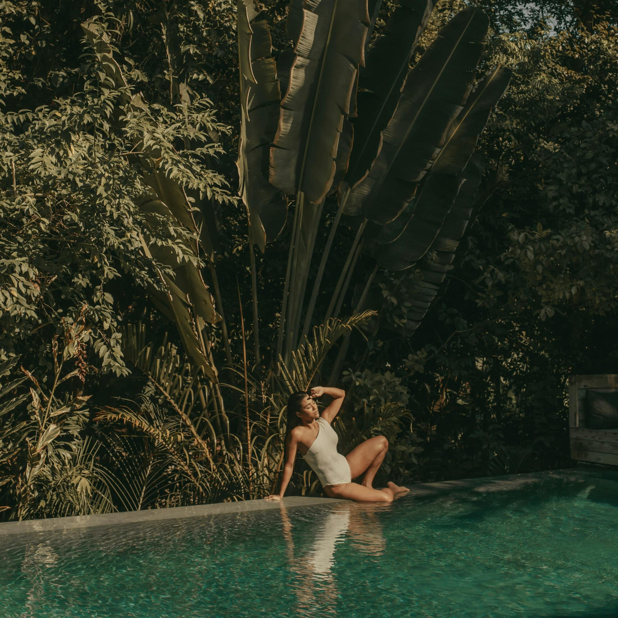 Woman in bathing suit relaxing at tropical pool