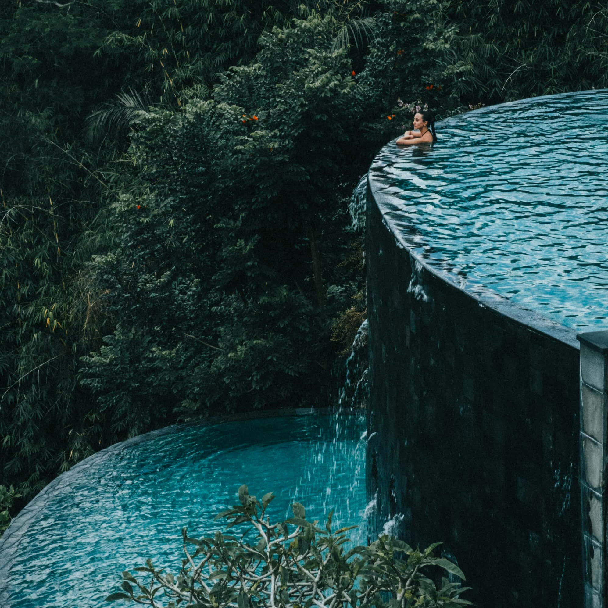 Woman at the edge of a two level pool surrounded by nature